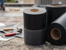 Roll of black EPDM reinforced perimeter fastening strip on a flat roof deck beside membrane roll