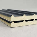 Cut end of an 80mm PIR insulated roof panel showing the rigid foam core between ribbed steel outer face and flat liner