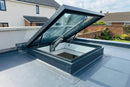 Electric opening flat roof skylight shown open on its chain actuator above an EPDM flat roof