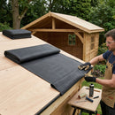 Craftsman laying EPDM rubber membrane on new wooden garden chalet flat roof - premium shed EPDM roof kit UK