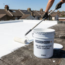Rubber Roof UK branded tub of white solar reflective coating being roller-applied to a felt flat roof