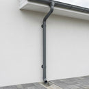 Anthracite grey round aluminium downpipe installed down a rendered wall with clips and shoe