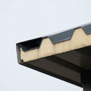 Eaves edge of a garage roof showing anthracite steel sheets with the bonded cream anti-condensation foam layer underneath