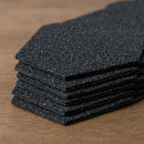 Close-up stack of black bitumen roof shingles showing granule texture