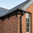 Black cast iron half round gutter and downpipe fitted to a Victorian brick roofline