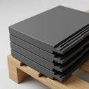 Close-up stack of smooth grey interlocking concrete roof tiles