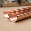 Close-up of cut copper half round guttering lengths showing the bright polished finish and half-round profile