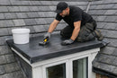 Roofer installing dark grey EPDM rubber membrane on the flat top of a slate roof dormer with a hand roller - EPDM dormer roof kit