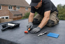 DIY EPDM installation kit tools in use on a rubber flat roof - seam roller, paint roller, knife and squeegee