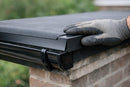 Black EPDM drip edge trim fitted along a rubber flat roof edge over a gutter on a UK brick house
