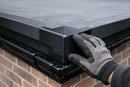 Black EPDM drip trim external corner fitted at the outside corner of a rubber flat roof edge over a gutter
