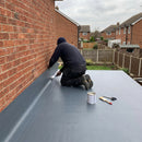 Installer rolling the one-piece EPDM membrane up the house wall to form the 150mm upstand on an extension flat roof