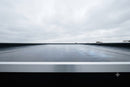Wide view along a smooth EPDM rubber flat roof with a metal edge trim under an overcast sky