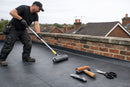 Professional EPDM installation kit in use - roofer pressing membrane with long-handled roller on a flat roof