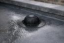 EPDM roof drain outlet with leaf grate installed flush in a dark grey rubber flat roof