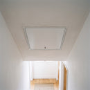 Fire-rated insulated loft hatch installed flush in a ceiling, viewed from below in a hallway
