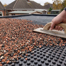 Lightweight green roof growing substrate being laid and levelled over a drainage board on a flat garden room roof