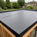 Black HDPE root barrier membrane laid out and overlapped across a flat garden-room roof deck, ready for the drainage layer before substrate is added