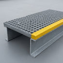 Close-up of the gritted anti-slip GRP mesh deck and yellow nosing edge on a step-over platform
