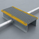 GRP step-over platform bridging an insulated pipe run on a grey single-ply flat roof
