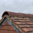 Handmade clay half round ridge tiles in Red Antique installed along a roof ridge line