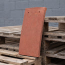 Single handmade clay plain roof tile in the Rustic Red colourway showing camber profile