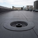 Black EPDM industrial roof drain connector bonded into membrane on a commercial flat roof