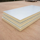 Stack of foil-faced rigid PIR insulation boards on a solid roof deck showing the foam core edge