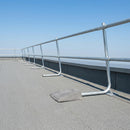 Freestanding galvanised steel guardrail edge protection installed along a flat roof perimeter