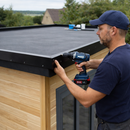 Roofer fitting black metal edge trim on garden room EPDM rubber flat roof - garden room roof kit UK