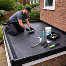Roofer rolling EPDM flat roof membrane on house extension with ClassicBond bonding adhesive and tools - EPDM kit UK