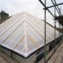 Reinforced woven polyethylene temporary roof cover dressed tightly over exposed roof timbers during refurbishment, secured with scaffolding alongside