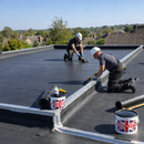 Two roofers installing complete EPDM garden room rubber roof kit with Rubber Roof UK adhesive - flat roofing UK
