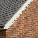 White uPVC decorative scalloped bargeboard fitted along a brick gable roof verge