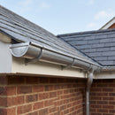 Natural zinc half round guttering installed along a slate roof eaves on a traditional brick house, correctly fixed with evenly spaced brackets